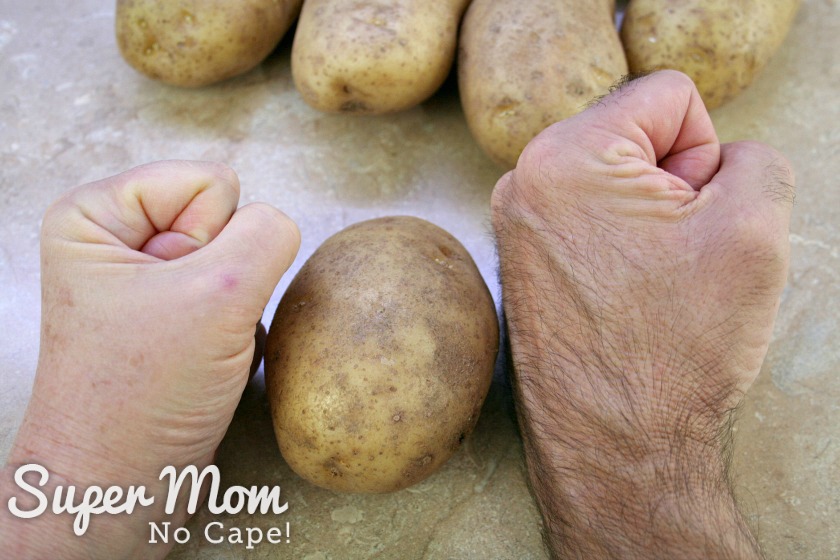 Photo of a woman's fist and a man's fist with potato in between