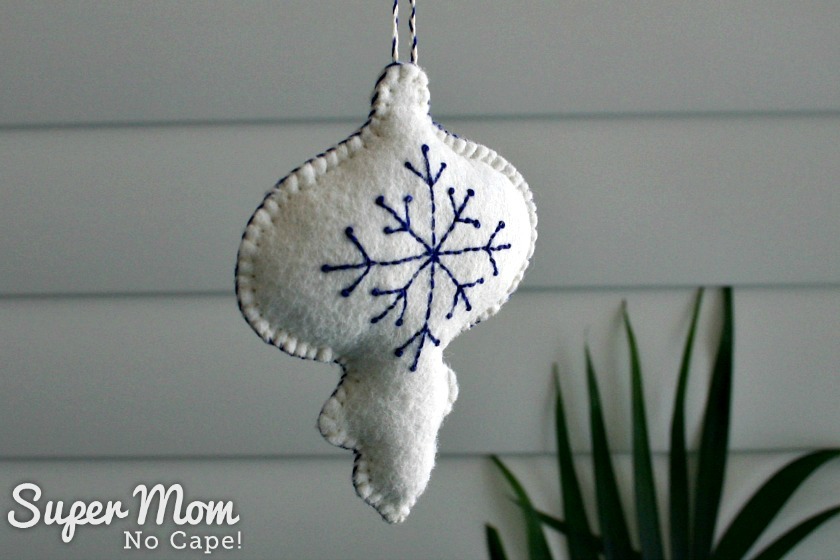 https://www.supermomnocape.com/wp-content/uploads/2018/07/View-2-of-White-Felt-Bauble-with-Blue-Embroidered-Snowflake.jpg