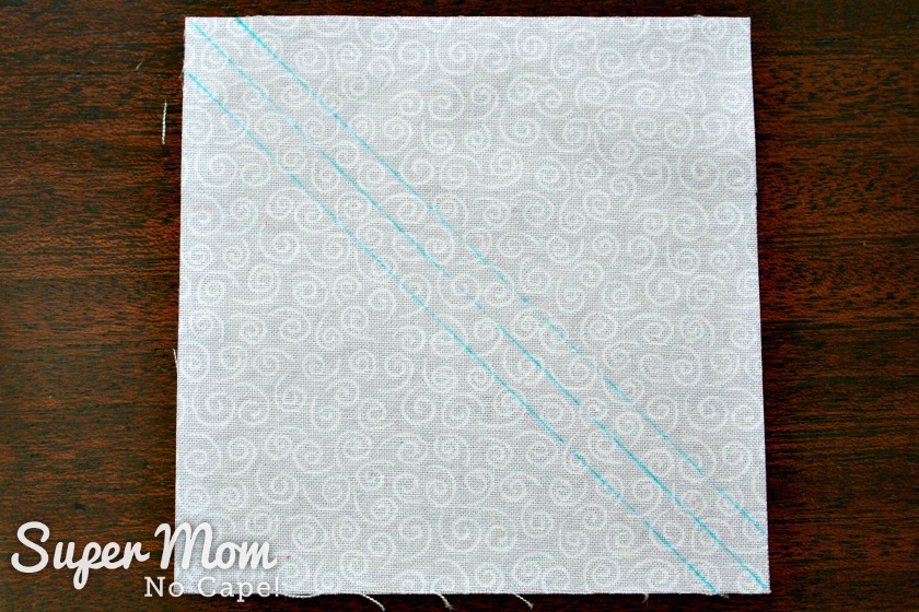  Diagonal lines drawn on white square of fabric