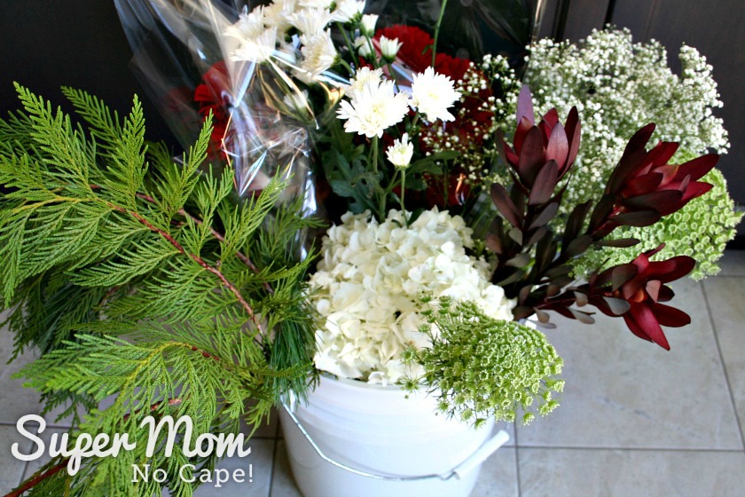 Lots of flowers in a white bucket to make a DIY Christmas Floral Arrangement