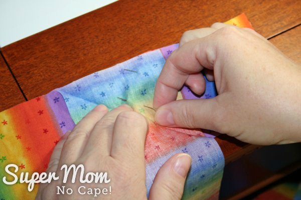 Adding the second pin to secure the two strips of striped fabric together