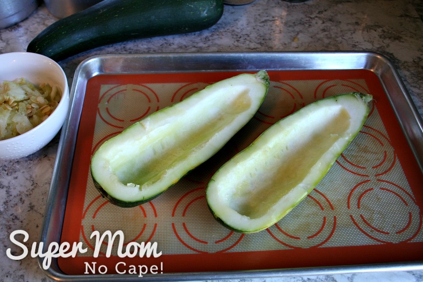 2 hollowed out halves of large zucchini on baking sheet