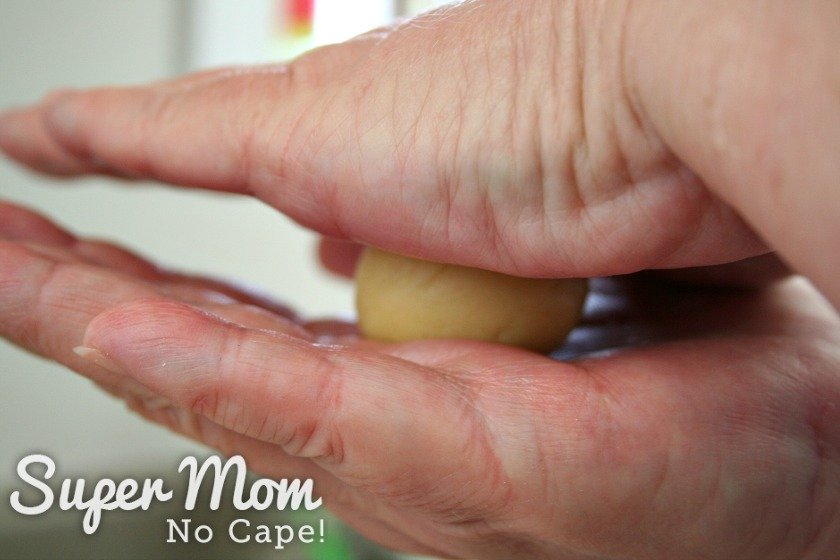 Ball of almond cookie dough being rolled between two hands