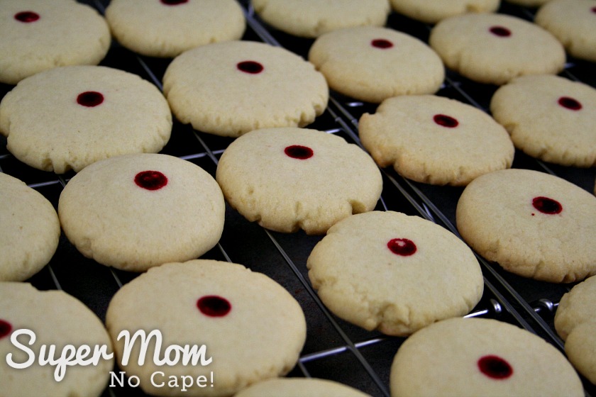 Red dot almond cookies cooling on racks